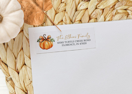 White envelope with pumpkin design and address on a woven mat with pumpkins
