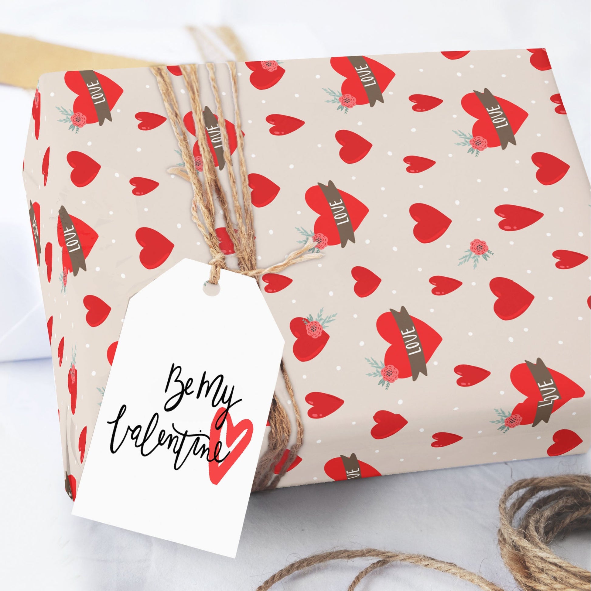 Gift wrapped in red heart patterned paper with 'Be My Valentine' tag on a white background